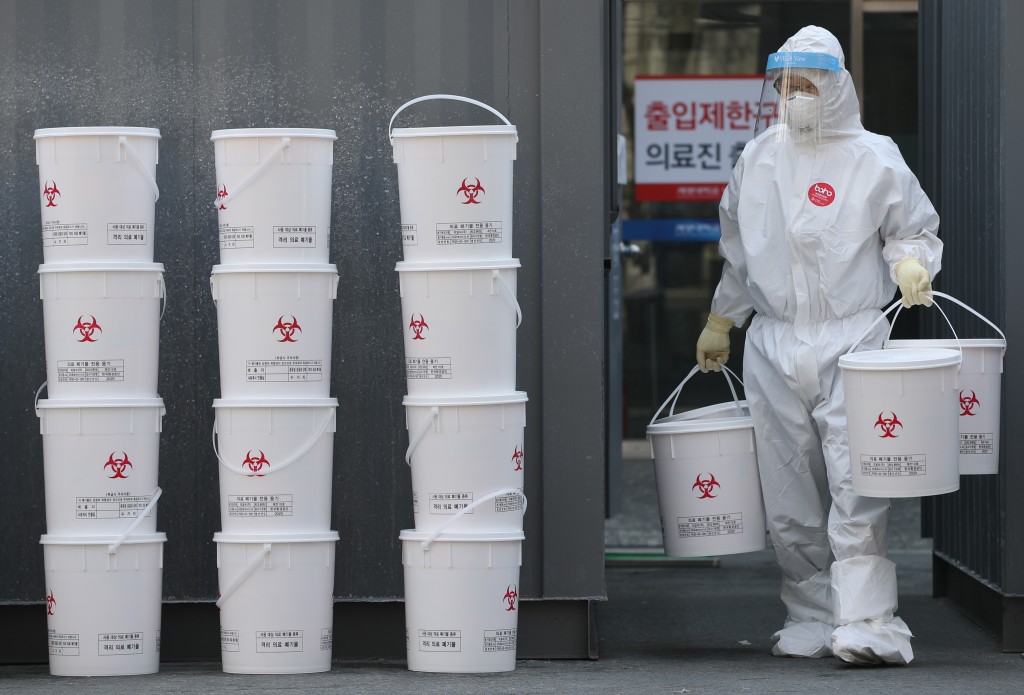 A　medical　worker　carrying　medical　waste　containers　at　a　hospital　in　Daegu