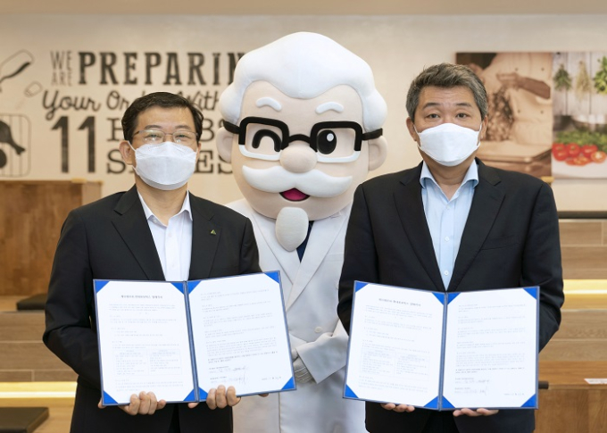 Hyundai　Robotics　COO　Seo　Yoo-seong,　left,　and　KFC　Korea　CEO　Eom　Ik-soo　sign　an　MOU　Oct　23　to　develop　an　automated　chicken-frying　process　incorporating　robots.