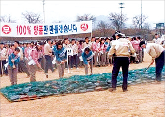 Samsung　employees　take　a　hammer　to　defective　phones　in　1995.　The　banner　reads:　We　will　make　100%　quality　products