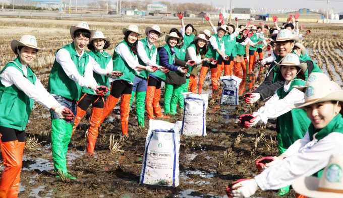 Volunteers distribute coffee compost made from Starbucks used coffee grounds to farms