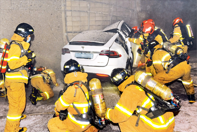 Firefighters at scene of Tesla X car crash and fire, in Seoul Dec. 9
