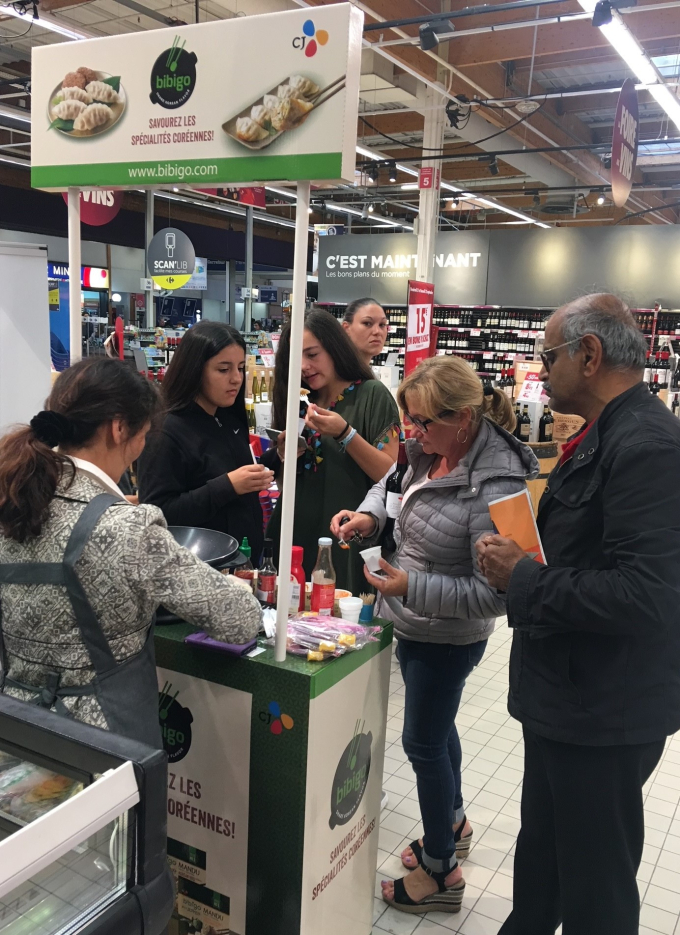 Shoppers　in　France　sample　Bibigo　at　a　supermarket　kiosk.