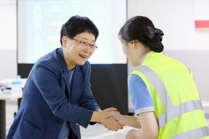 HomePlus Chief Executive Lim Il-soon, on left, shakes hands with an employee.