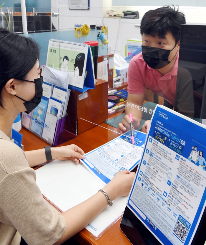 An　office　worker　getting　information　on　personal　loans　at　a　retail　bank　in　Seoul.