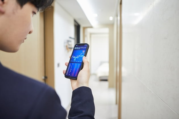 A　Korean　millennial　checking　stock　performance　on　his　phone　(Courtesy　of　Getty　Images　Bank).