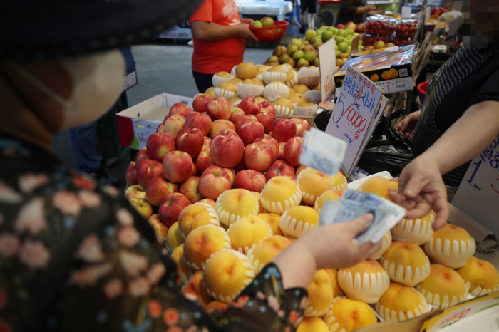A　consumer　buys　fruit　at　a　marketplace　in　Seoul