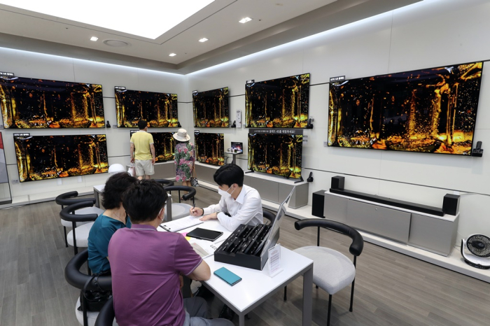 An LG Electronics’ salesperson discusses products with customers at one of LGE's home appliance shops in Seoul