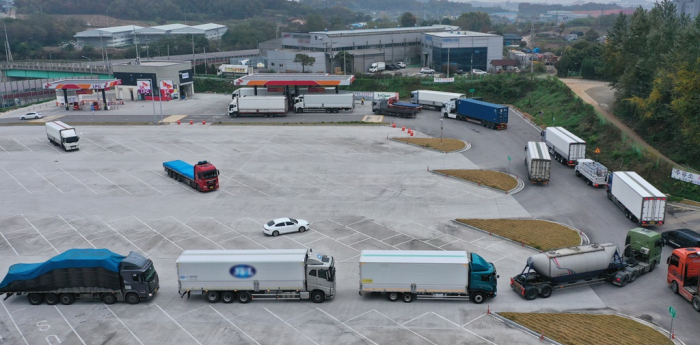 Cargo trucks line up to replenish diesel exhaust fluid at a gas station in South Korea