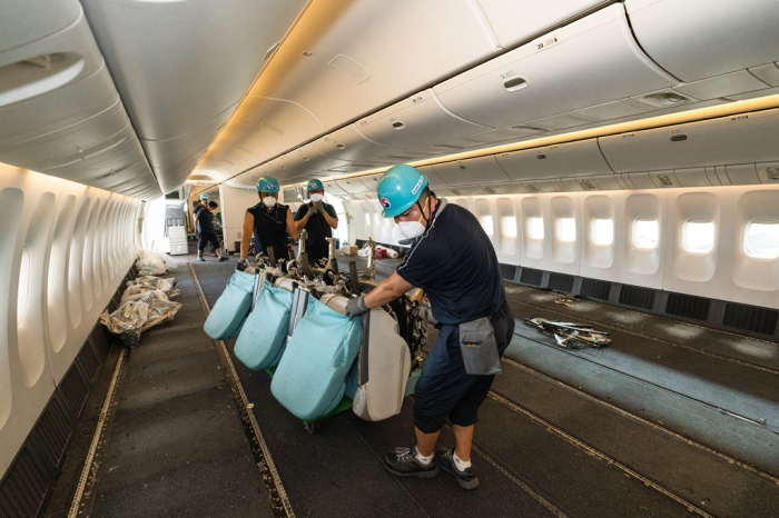 Korean　Air　employees　remove　seats　from　an　airliner　to　enable　cargo　space　for　floor　loading.