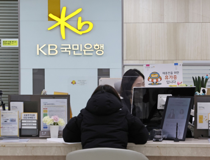 A　customer　speaks　with　a　teller　at　Kookmin　Bank,　South　Korea’s　largest　lender,　in　Seoul　after　the　central　bank　raises　interest　rates　in　January.