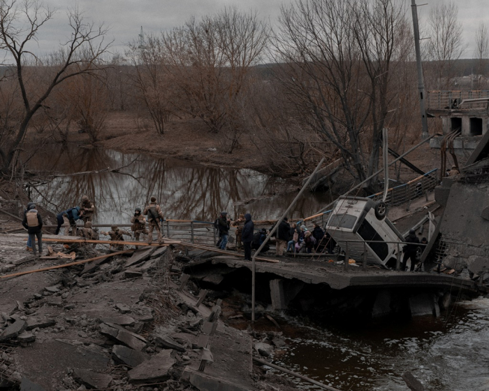 People cross a makeshift bridge as they flee the city of Irpin in the Kyiv region, Ukraine on March 5 (Courtesy of Reuters, Yonhap)