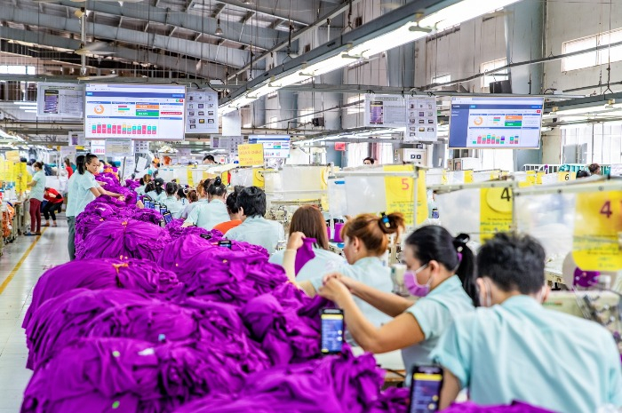 A　factory　operated　by　Hansae　Co.　where　workers　can　check　their　performance　on　overhead　monitors