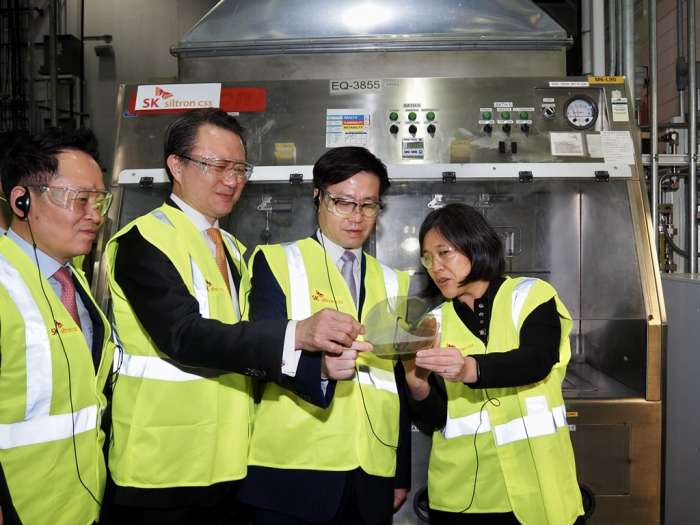 From left, SK Siltron CEO Jang Yong-ho, SK E&S Vice Chairman & CEO Yu Jeongjoon, South Korean Trade Minister Yeo Han-koo and US Trade Representative Katherine Tai look at a wafer produced at SK Siltron’s Auburn factory on March 16.