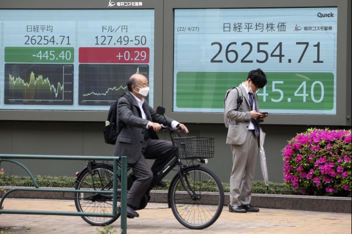 A　Japanese　man　cycles　past　a　stock　market　tracker　in　Tokyo