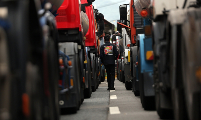 A　member　of　the　unionized　truckers　passes　by　trucks　parked　near　the　Yeosu　Industrial　Complex