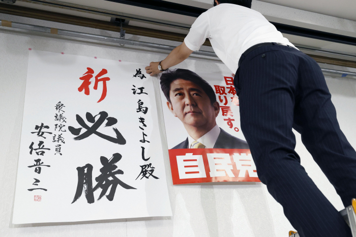 A　member　of　the　Liberal　Democratic　Party　puts　up　a　poster　of　former　Prime　Minister　Shinzo　Abe　in　Yamaguchi　prefecture　on　July　10 