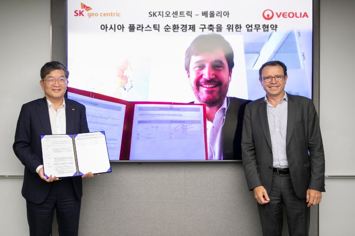 SK　Geo　Centric　CEO　Na　Kyung-soo　(left),　senior　executive　vice　president　of　Veolia's　Asia　region　Christophe　Maquet　(on　screen);　and　Hervé　Péneau,　Veolia’s　country　director　for　Korea　(Courtesy　of　SK　Geo　Centric)
