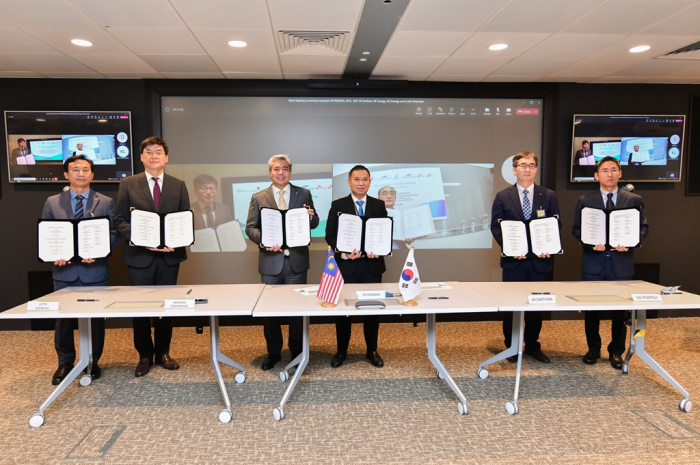 Lotte Chemical Vice President, Environment Management Division Park In-chol (from front left), Samsung Engineering Executive Vice President, Solution Business Division Park Cheonhong, Petronas Executive Vice President and Chief Executive Officer of Upstream, Datuk Adif Zulkifli, Petronas Head of Carbon Management Emry Hisham, SK Earthon Executive Vice President, Technical Center Han Youngju and GS Energy Vice President, Hydrogen & New Business Division Lee Sunghoon take a picture after signing an MOU on Aug. 2, 2022, at Petronas Twin Tower in Kuala Lumpur. SK Energy Executive Vice President, Energy Net Zero Office Hong Jeongeui (from left on screen) and Samsung Heavy Industry Vice President, Global Business Team Kim Jinmo join the signing ceremony online (Courtesy of Lotte Chemical)