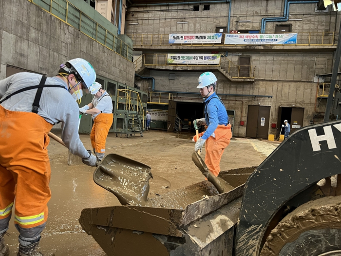 POSCO　employees　remove　mud　at　its　Pohang　plant. 