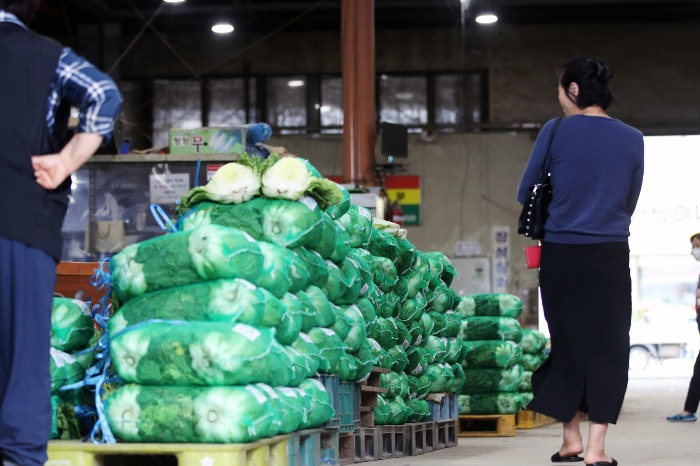 A　shopper　considers　whether　to　buy　napa　cabbage　after　checking　the　price　at　a　market　in　Gwangju　on　September　13