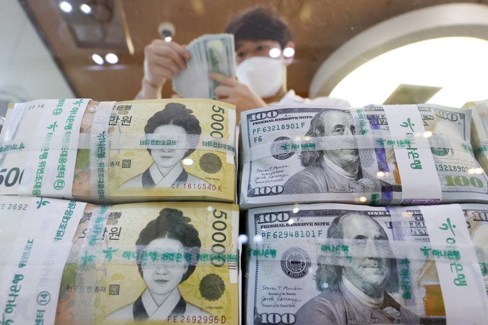A　Hana　Bank　official　organizes　bundles　of　South　Korean　won　and　dollars　at　its　headquarters　in　Seoul　on　Sept.　22,　2022　(Courtesy　of　News1)