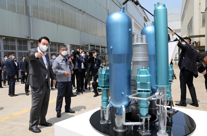 Korean President Yoon Suk-yeol (left on the front) looks at a model of a domestically developed nuclear reactor at Doosan Enerbility’s plant