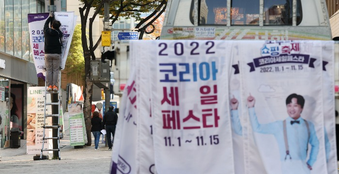 Workers take down the 2022 Korea Sale Festa promotional banners in the streets of Myeongdong