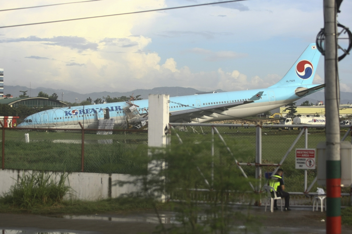 A　security　guard　keeps　watch　beside　a　damaged　Korean　Air　plane　after　it　overshot　the　runway　at　the　Mactan-Cebu　International　Airport　in　Cebu,　central　Philippines　early　Oct.　24,　2022　(Courtesy　of　AP,　Yonhap)