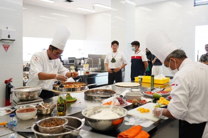 Kang　Leo　(second　from　left),　a　star　Korean　chef　and　head　of　the　Lotte　Mart　Food　Innovation　Center,　passes　on　Korean　food　recipes　to　Indonesian　staff,　who　are　former　hotel　cooks,　at　the　Food　Innovation　Lab　located　at　Lotte　Grosir　Pasar　Rebo　in　Jakarta,　on　Oct.　14,　2022　(Courtesy　of　Lotte　Mart)
