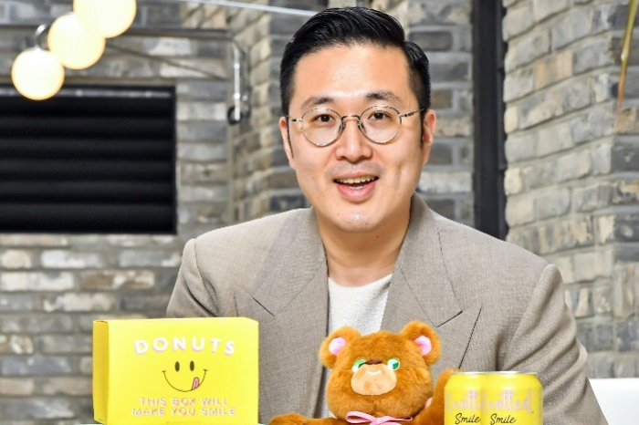 CEO　of　GFFG　Lee　Joon-beum　poses　with　coffee　and　beer　products　featuring　Cafe　Knotted　designs