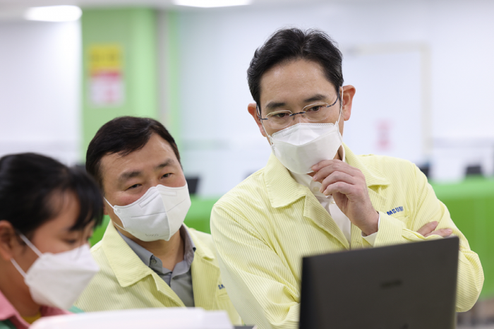 Samsung　Electronics　Chairman　Jay　Y.　Lee　(right)　takes　a　look　at　a　smartphone　production　line　at　its　Vietnamese　plant　on　Dec.　22,　2022　(Courtesy　of　Samsung　Electronics)