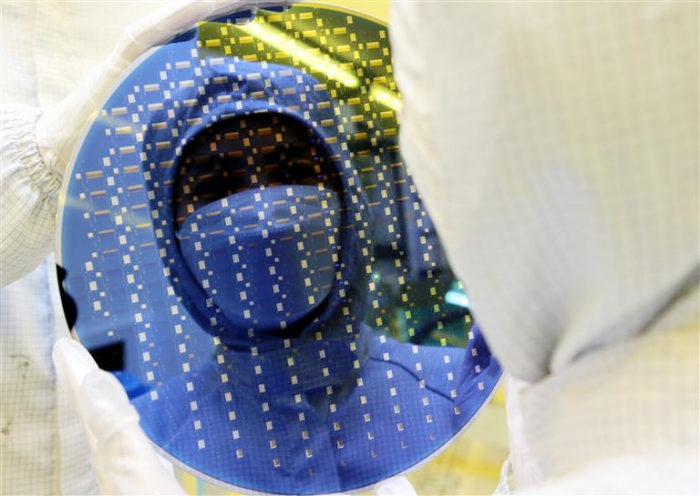 A Samsung employee looks at a chip wafer