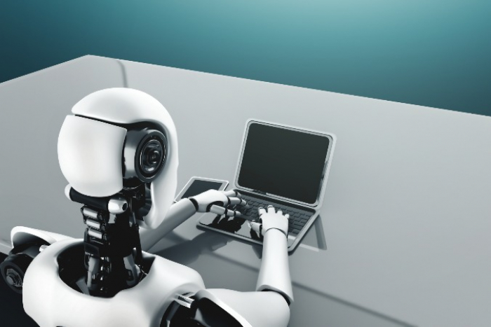 Robot humanoid backed by AI-thinking brain uses a laptop in a future office (Courtesy of Getty Images)
