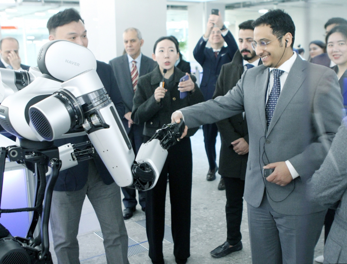 Alhassan Alhazmi, general manager of Saudi Arabia's AI administration SDAIA, shakes hands with Ambidex, Naver's robot arm, at the Naver 1784 building in Pangyo, Korea on Feb. 27, 2023