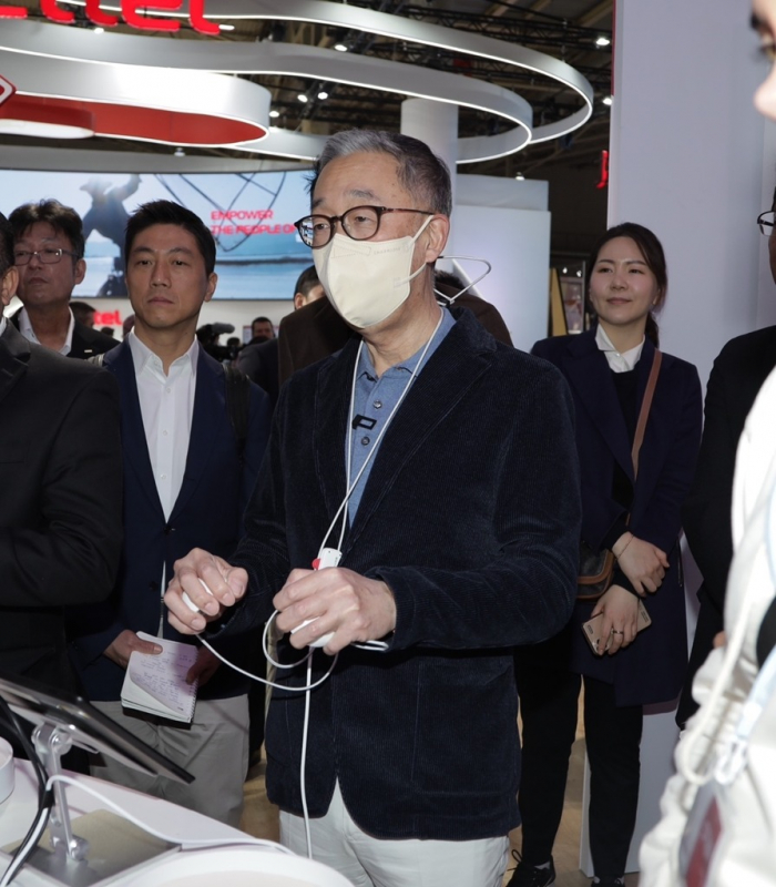Doosan　Group　Vice　Chairman　Park　Geewon　(middle)　tries　out　a　sensor　applied　with　6G　technology　at　NTT　Docomo’s　booth　at　MWC　Barcelona　on　Feb.　28,　2023　(Courtesy　of　Doosan)