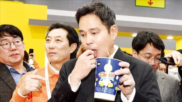 Shinsegae Vice Chairman Chung Yong-jin (center) samples a snack from its convenience store unit E-Mart24 at a product fair on March 8, 2023, in Seoul
