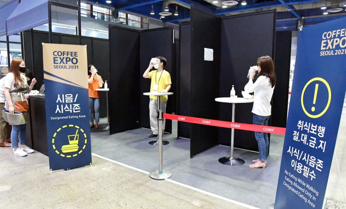 Visitors sample coffee under social distancing measures at Coffee Expo Seoul 2021 when South Korea imposed strict rules against COVID-19