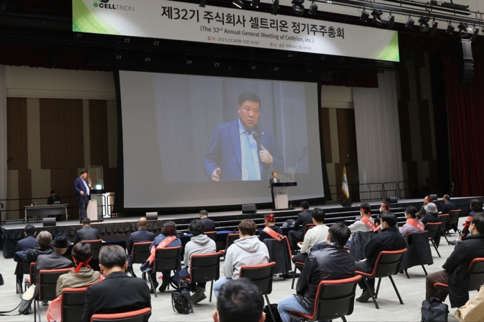 Celltrion　founder　Seo　Jung-jin　(left　on　the　stage　and　onscreen)　speaks　to　stockholders　at　the　company’s　shareholder　meeting　on　March　28,　2023　(Courtesy　of　Celltrion)