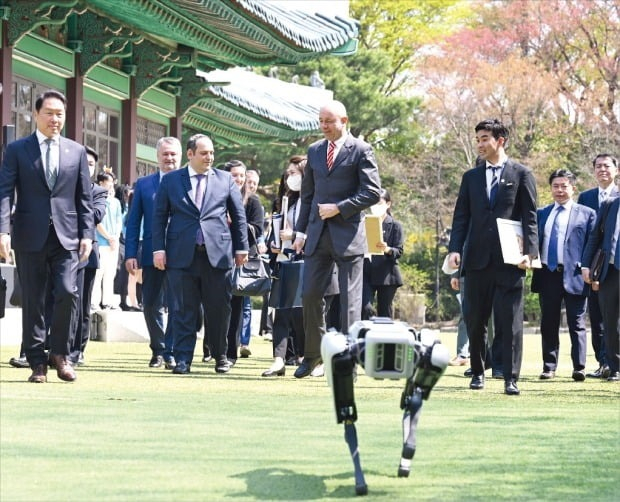 Korea Chamber of Commerce and Industry Chairman Chey Tae-won (left) and an inspection team from the Bureau International des Expositions (BIE) including Patrick Specht (third from front left), head of the organization’s administration and budget committee, head to a luncheon at the Shilla Hotel in Seoul on April 3, 2023, led by the dog-like robot Spot