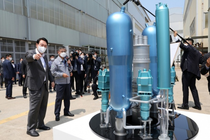 South　Korean　President　Yoon　Suk　Yeol　(left,　at　front)　looks　at　a　model　of　a　domestically　developed　nuclear　reactor　at　a　Doosan　Enerbility　plant　on　June　22,　2022