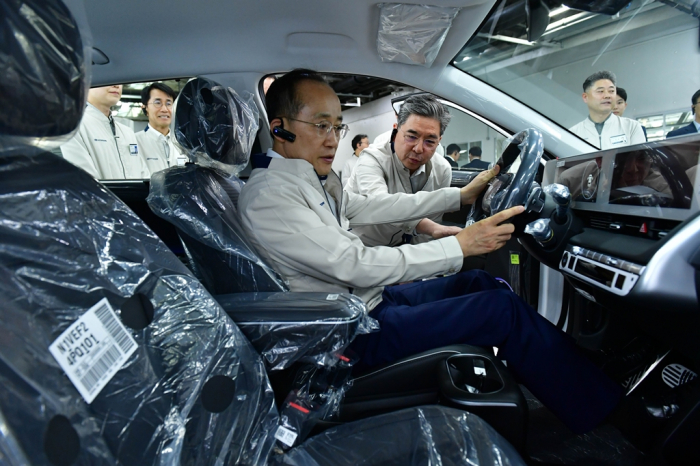 Finance Minister Choo Kyung-ho, in the driver's seat, listens as Hyundai Motor CEO Chang Jae-hoon explains the workings of a new EV on an assembly line at the carmaker's Ulsan plant on May 9, 2023