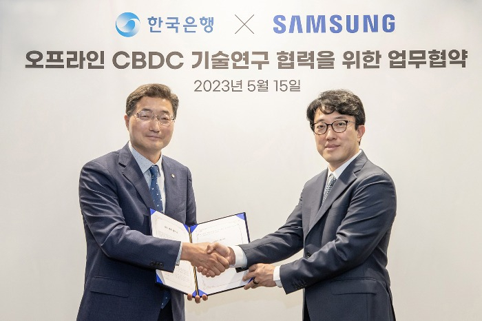 Lee　Seung-heon,　BOK’s　senior　deputy　governor,　(on　left)　and　Choi　Won-joon,　executive　vice　president　of　the　mobile　experience　division　of　Samsung　Electronics,　at　an　MOU　signing　ceremony　on　May　15,　2023.　(Courtesy　of　Samsung　Electronics)