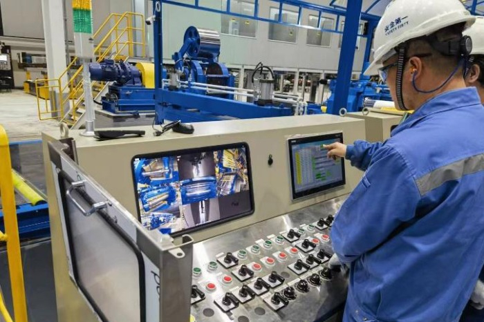 Workers　at　POSCO-CSPC,　a　processing　center　in　Jiangsu　Province,　China,　operating　specialized　slitters　for　giga　steel　manufacturing