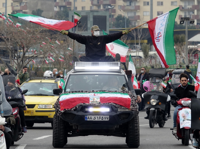 Citizens in Tehran march while holding flags in Azadi Square in February 2022 during a rally commemorating the 43rd anniversary of the Islamic Revolution