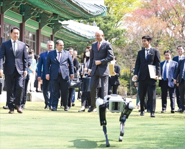 Dog-like　robot　Spot　leads　SK　Chairman　Chey　Tae-won　(left)　and　an　inspection　team　from　the　BIE　to　a　luncheon　at　the　Shilla　Hotel　in　Seoul　on　April　3,　2023