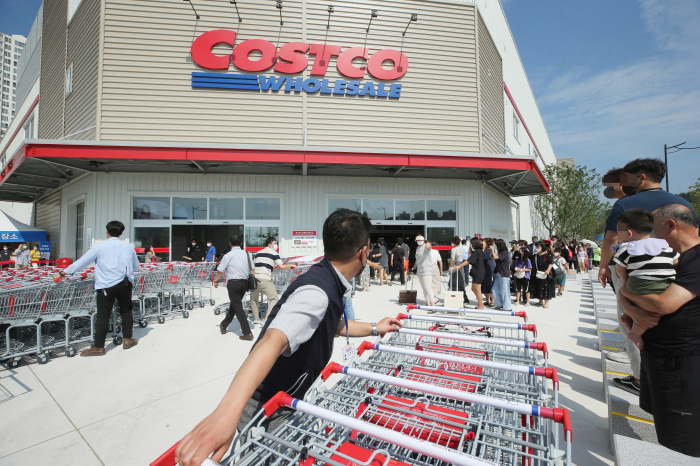 Costco workers move shopping carts to the entrance of its outlet in Gimhae, South Gyeongsang Province