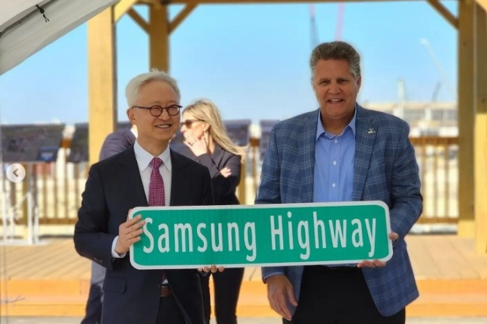 Samsung　Electronics’　Device　Solutions　President　Kyung　Kye-hyun　holds　a　Samsung　Highway　road　sign　with　Williamson　County　Judge　Bill　Gravell　near　Samsung’s　new　foundry　factory　construction　site　in　Taylor,　Texas　in　January　2023