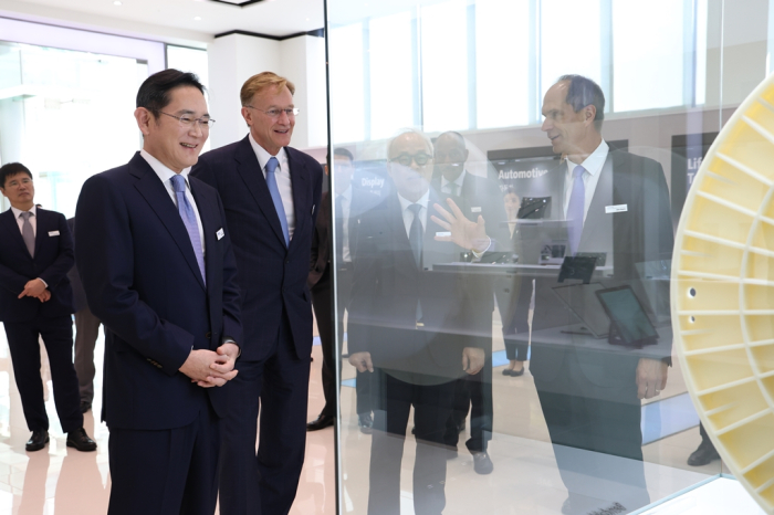 Samsung Chairman Jay Y. Lee (second from left) and Corning CEO Wendell Weeks (beside Lee, center) tour Corning's demo room in Korea
