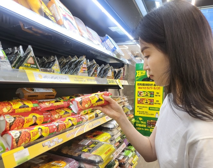 A　shopper　picks　up　a　gimbap　roll　in　a　convenience　store
