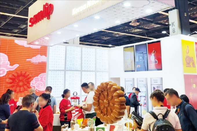 An oversized model of a traditional brown, round yakgwa on display at SPC Samlip's booth for the 2023 Anuga Food Fair
